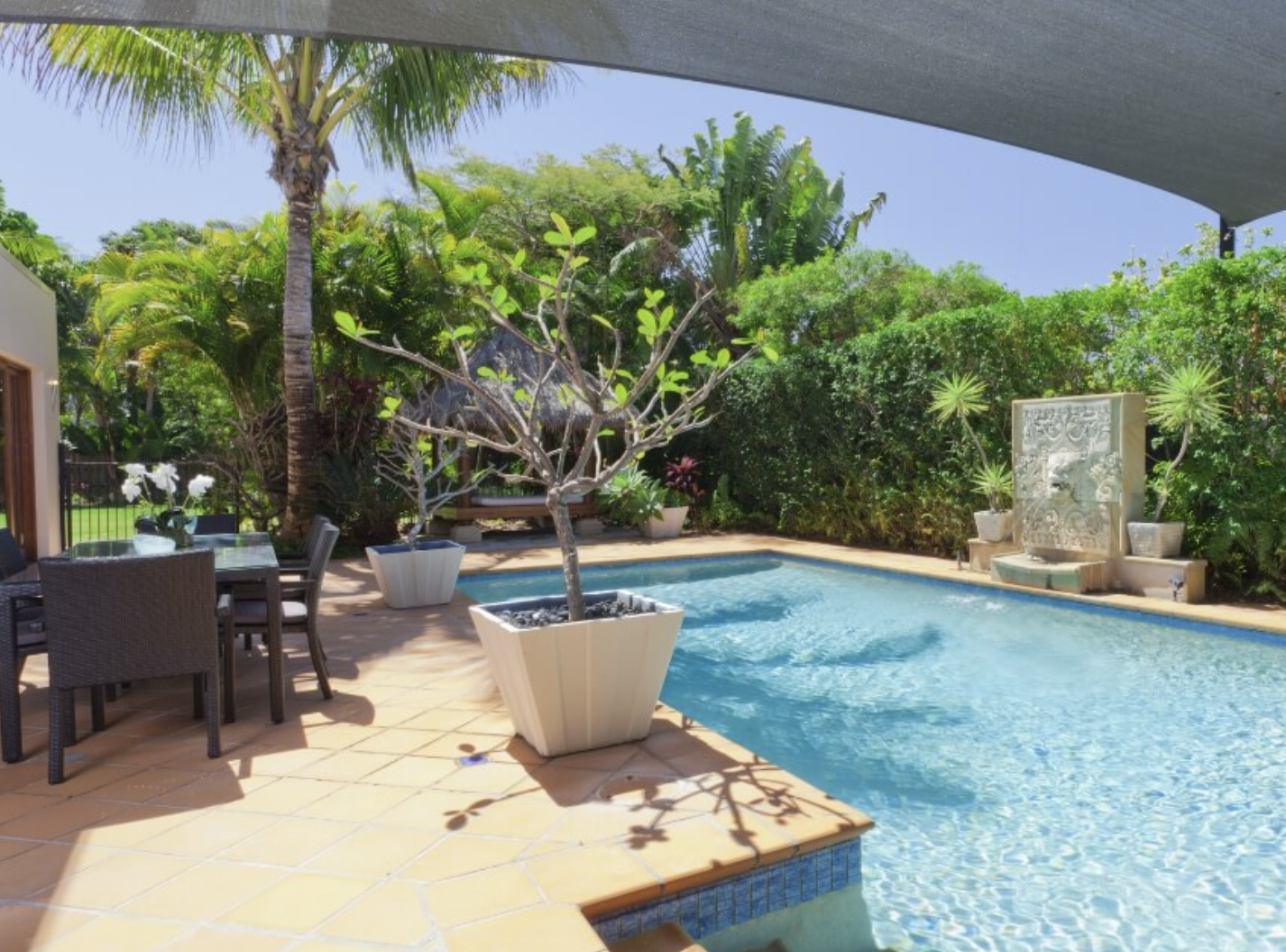  A backyard pool surrounded by a table and chairs, creating a relaxing outdoor space for leisure and gatherings.